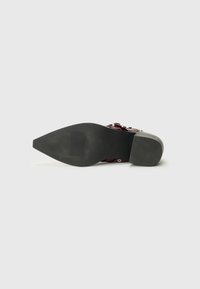 Sandale à talon rouge avec une semelle en caoutchouc noire. Présente un design texturé et des accents en métal argenté. Bout pointu et style à dos ouvert.