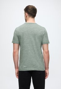 T-shirt κοντομάνικο με στρογγυλή λαιμόκοψη σε μελανζέ πράσινο ύφασμα. Διαθέτει κανονική γραμμή και λεία υφή χωρίς ορατά σχέδια ή επιπλέον λεπτομέρειες.