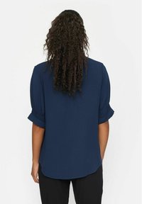 Marineblå bluse med korte, elastiske ærmer, en glat tekstur og en løs pasform, der har en buet kant og en afslappet silhuet.