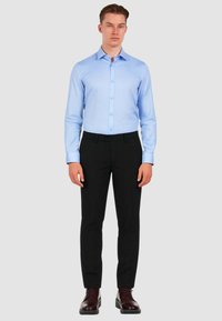 Camicia blu chiaro a maniche lunghe con bottoni abbinata a pantaloni neri e scarpe bordeaux. Vestibilità slim, tessuto liscio e design del collo classico.