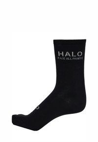 Svart ankelstrumpa gjord av mjukt, elastiskt material. Har texten "HALO" och "FACE ALL FRONTS" i grått stickat på manschetten.