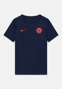 Mørkeblå kortermet treningstrøye med rød Nike-swoosh og sirkulært emblem på brystet.