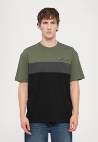 Tricou din bumbac de culoare verde măslin, gri și negru. Mânici scurte cu un decolteu rotund și un mic logo pe partea stângă. Croială dreaptă.