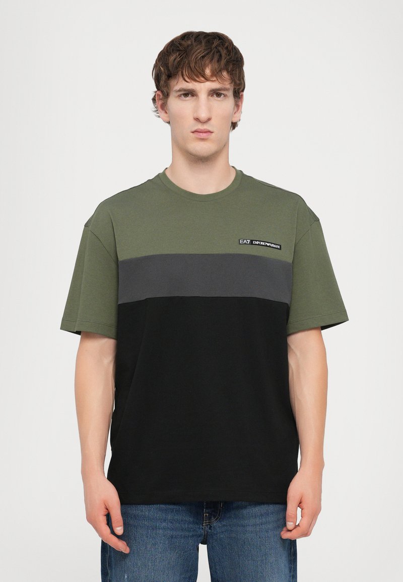 Tricou din bumbac de culoare verde măslin, gri și negru. Mânici scurte cu un decolteu rotund și un mic logo pe partea stângă. Croială dreaptă.