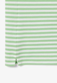 Grön- och vitrandig tyg med en texturerad yta; har en lätt sidofuts vid fållen.