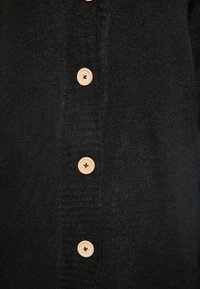 Cardigan nero realizzato in morbido tessuto a maglia, con una chiusura anteriore a bottoni in legno e dettagli a coste lungo il risvolto.