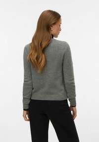 Sivi džemper s dugim rukavima, pletena tekstura, rebrasti rubovi na manžetama i donjem dijelu. Nošen s crnim hlačama, prikazujući jednostavan i klasičan dizajn.