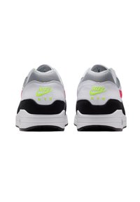 Sneakerii Nike Air au un superior din plasă albă, accente din suede negru, o talpă intermediară roz și un logo verde neon pe călcâi. Solele durabile din cauciuc.