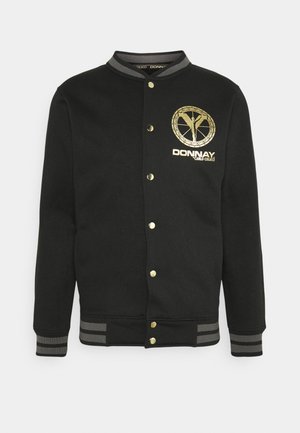 Black varsity jacket with gold snap buttons, striped gray cuffs and collar, and gold Donnay logo on the left chest.