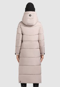Dlhý, svetloružový prešívaný kabát s kapucňou, s horizontálne prešívanými sekciami, okrúhlym logom a čiernymi elastickými manžetami.