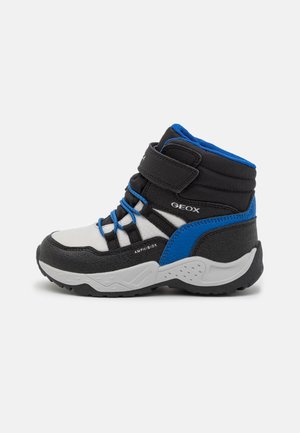 Stivaletti alla caviglia neri e grigi con accenti blu, dotati di cinturino in velcro, pannelli in mesh e suola in gomma testurizzata progettata per la presa.