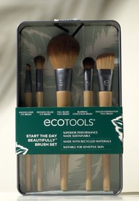Ensemble de cinq pinceaux de maquillage Ecotools avec des poignées en bambou et des poils doux, emballés dans une boîte en métal transparent avec des accents verts et blancs.