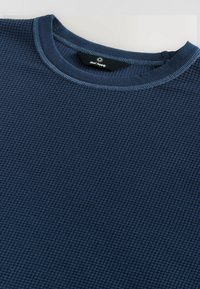 Marineblå langærmet t-shirt lavet af struktureret stof, med en rund halsudskæring med kontrasterende syninger og et mærke i nakken.