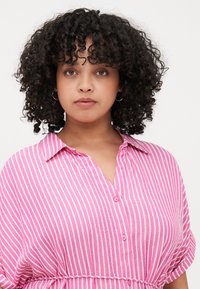 Ροζ και λευκή ριγέ πουκάμισο με κοντό μανίκι, κουμπωτή μπροστινή πλευρά, γιακά και ζωνάκι στη μέση. Υφασμάτινη σκεπή, χαλαρός σχεδιασμός.