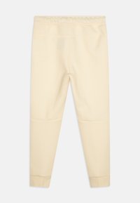 Beiga leggings med en mjuk textur, elastisk midjeband och tapered design; har sydda sömmar och manschetter vid anklarna.