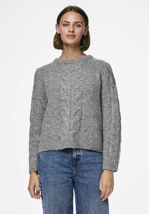 Pull en tricot gris avec un col rond et des manches longues, présentant des motifs texturés et une taille légèrement courte. Associé avec un jean bleu.