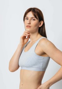 Grauer Sport-BH mit rundem Ausschnitt, breiten Trägern und weichem Material. Verfügt über eine enganliegende Passform und ein kontrastierendes Band mit Logodetails.