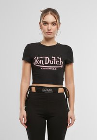 Čierne skrátené tričko s krátkymi rukávmi, so srdcovým logom "Von Dutch Originals" v ružovej farbe. V kombinácii s čiernymi nohavicami a pásom s logom.