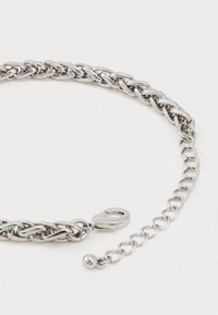 Colar de corrente torcido em tom prateado, com fecho lagosta e extensão ajustável com um pequeno bead redondo em metal no final.