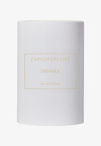 Zarkoperfume Dreamer eau de parfum i en sylinderformet hvit flaske med gullbokstaver, som har et minimalistisk design og glatt tekstur.