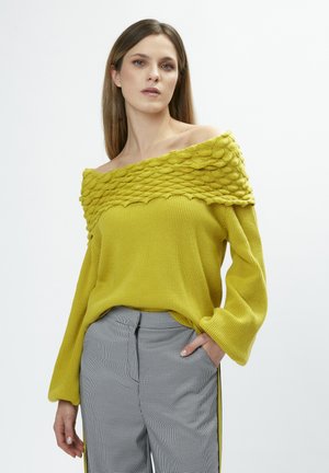 Geel off-the-shoulder sweater met een textuur ribbel ontwerp, voorzien van lange mouwen en een boxy fit, gecombineerd met geruite broek.
