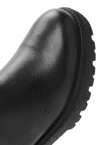Scarpa in pelle nera con superficie texturizzata, punta arrotondata e suola spessa e robusta con un pronunciato motivo di battistrada.