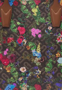 Borsa a tracolla con stampa floreale su sfondo marrone scuro, caratterizzata da fiori colorati, piante verdi e dettagli in pelle marrone.