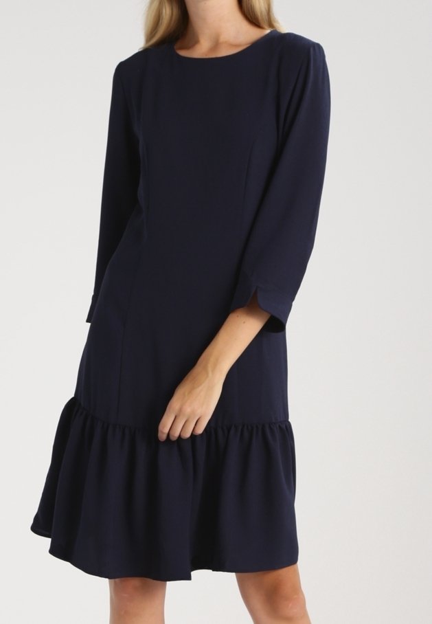 Tyrkysové šaty s kulatým výstřihem, tříčtvrtečními rukávy a rozšířeným volánkovým lemem. Vyrobeno z hladké látky s minimem detailů.