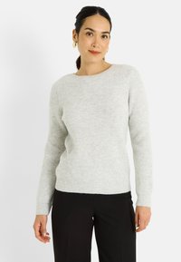 Suéter gris claro acanalado con cuello redondo, mangas largas y textura suave, combinado con pantalones negros. Sin patrones ni detalles visibles.