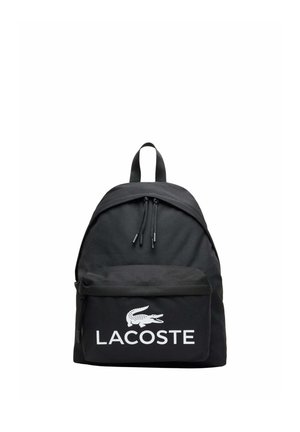 Zaino nero con tasca frontale con zip, che presenta il logo Lacoste bianco e il nome del marchio, doppie zip e maniglia superiore per il trasporto.