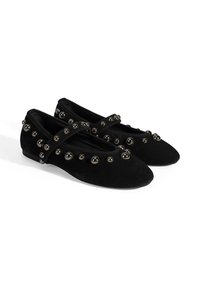 Schwarze Wildlederballerinas mit runder Zehenpartie, dekorativen silberfarbenen Perlen und einem Kreuzriemen über dem Spann. Glatte Textur und minimaler Absatz.