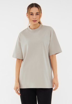 Světle šedé oversized tričko s krátkým rukávem a kulatým výstřihem, vyrobené z měkké bavlny, s volným střihem.