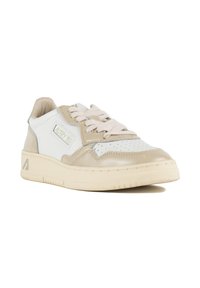 Sneaker bassa bianca e beige in pelle liscia, con area della punta traforata, lacci piatti e suola in gomma texturizzata con accento logo.