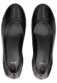 Svarta läderballerina med en glänsande svart rund tå. Har en mjuk textur och samlad detaljering vid hälen med en röd accent nära baksidan.