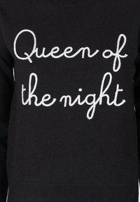 Maglione nero a maglia con la frase "Regina della notte" in filo argentato, dotato di colletto rotondo casual e orlo a costine.