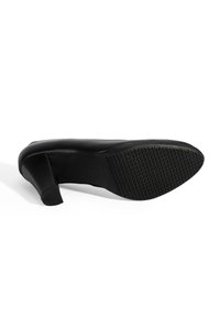 Zwarte hoge hak met een gestructureerde rubberen zool, een soepel leren bovenwerk en een chunky hak ontwerp. Geen zichtbare merkdetails.
