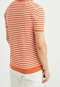 Kortärmad, orange och vit randig stickad polo skjorta, med en ribbad halsringning och nederkant, samt en texturerad tyg och åtsittande passform.