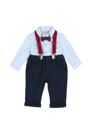 Tenue de bébé avec chemise bleu clair boutonnée, bretelles rouges, nœud papillon à carreaux avec motifs de fête et pantalon bleu marine aux revers roulés.