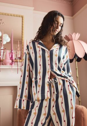 Stribede pyjamasæt med blå og hvide vertikale striber og mønster af røde og gule stjerner. Blødt stof, løst fit og knaplukning.