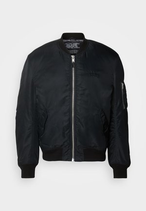 Bomber jacket in nylon nero con chiusura a zip, polsini a costine e tasca con zip sulla manica sinistra. Texture liscia e leggera.