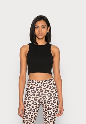 Topo de tanque preto, curto, combinado com leggings de cintura alta com um padrão de estampa de leopardo em bege e castanho. Textura de tecido suave.