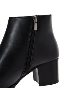 Zwarte leren enkelboot met een zijrits, een gladde oppervlakte, een gemiddelde blokhak en een slanke silhouet voor een aansluitende uitstraling.