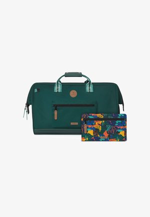 Sac de voyage vert foncé avec poche avant zippée et poignée, accompagné d'une pochette plus petite à motifs colorés avec une fermeture éclair frontale.