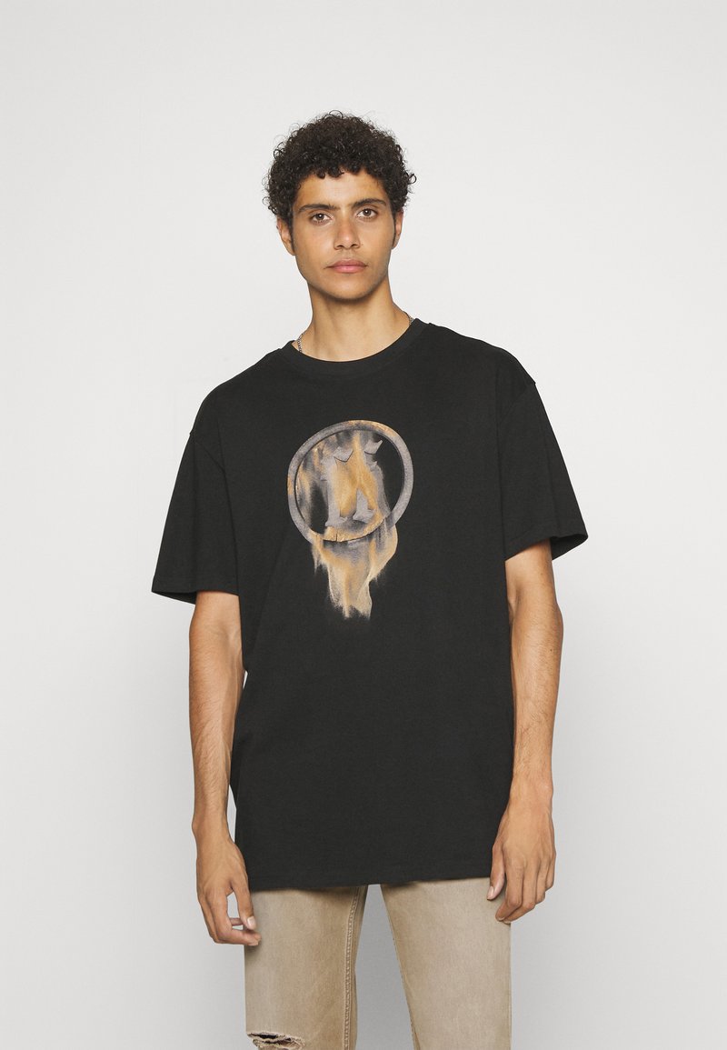 T-shirt en coton noir à manches courtes, avec un graphique circulaire dans des tons beige et gris. Coupe décontractée, col rond, design simple.
