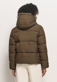 Ciemnooliwkowa kurtka puchowa z kapturem, z pikowanymi sekcjami, miękką teksturą i lekko skróconym krojem.