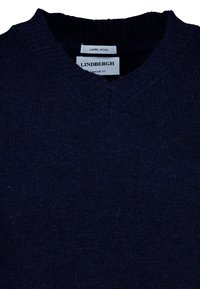 Marineblauer V-Ausschnitt-Pullover aus Lammwolle mit geripptem Kragen und weicher Textur. Die Etiketten zeigen "LINDBERGH" und "LAMBWOOL" zur Materialidentifikation.