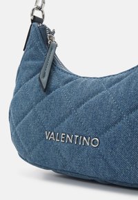 Quiltad denimaxelväska i blått med silverfärgad hårdvara, med en framträdande "Valentino"-logotyp och dragkedjestängning med läderdetaljer.