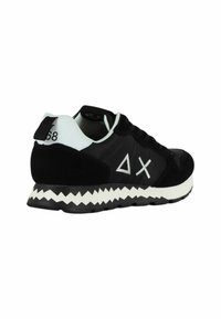 Scarpa da ginnastica nera con accenti bianchi, dotata di una suola zigzag, tomaia in suede e sintetico, e dettagli con logo geometrico.
