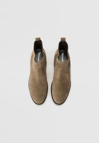 Bottines en suède marron avec semelles en caoutchouc noir, panneaux élastiques sur les côtés et une languette au dos. Texture lisse avec un design à bout arrondi.