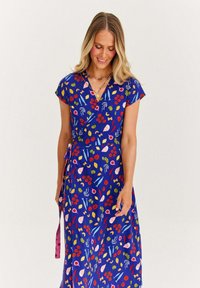 Modré zavinovací šaty s krátkými rukávy, zdobené živým květinovým vzorem v červené, růžové, žluté a zelené barvě na hladkém, splývavém materiálu.